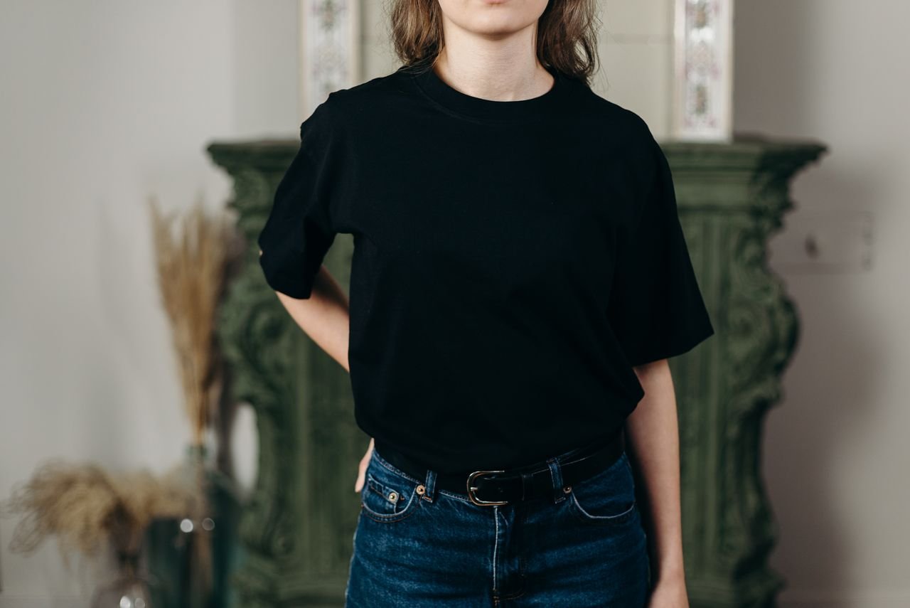 Home Faceless model in black t-shirt and jeans showcasing minimalist fashion style indoors.