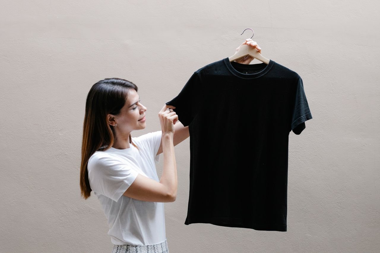Home Side view of positive female wearing casual outfit standing with black shirt against gray background